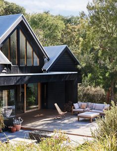 a black house with lots of windows on the roof and patio furniture in front of it