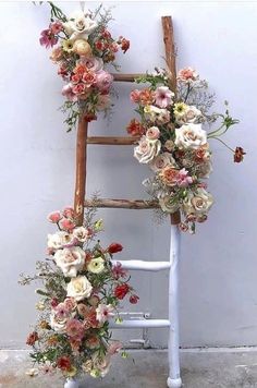 an old ladder decorated with flowers and greenery