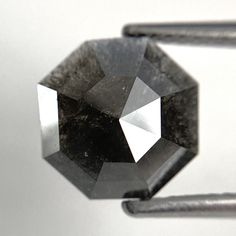 a black diamond sitting on top of a piece of metal