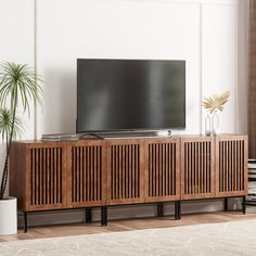 a flat screen tv sitting on top of a wooden entertainment center in a living room