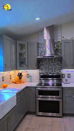 a kitchen with stainless steel appliances and blue lights on the counter tops, along with white tile flooring