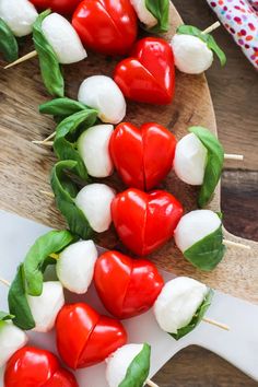 several red and white peppers on skewers with green leafy leaves attached to them