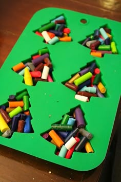 a green tray filled with crayons on top of a wooden table