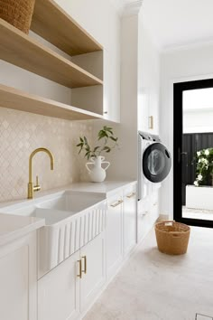 a laundry room with white cabinets and open shelving above the sink is a washer and dryer