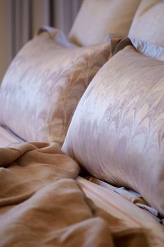 a bed with two pillows on top of it and a blanket over the headboard