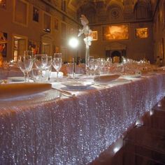 the long table is set with wine glasses and place settings