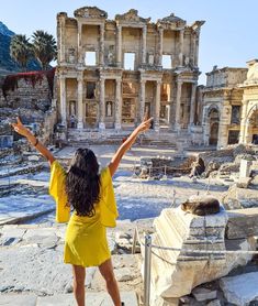 a woman standing on top of a stone walkway in front of an old building with columns