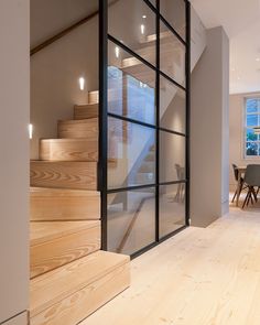 the interior of a modern home with wood floors and glass doors that lead to an upstairs dining area