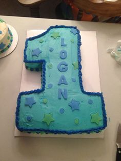 a blue and green birthday cake with the number one on it's side sitting on a table