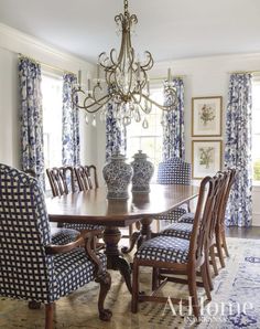 a dining room table with blue and white chairs in front of the chandelier