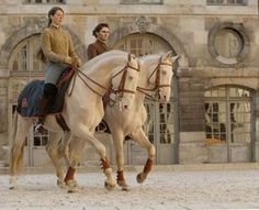 two women riding horses in front of a building