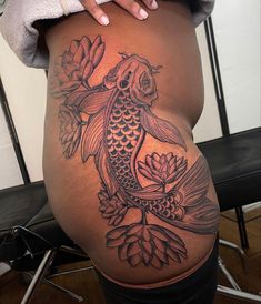 a woman's stomach with a koi fish tattoo on her belly and lotus flowers