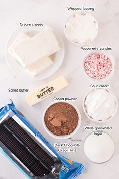 the ingredients needed to make an ice cream sandwich on a white marble counter top, including chocolate, marshmallows, whipped cream and sprinkles