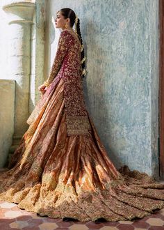 a woman in a long dress leaning against a wall with her back turned to the camera