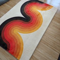 an area rug with multicolored waves on top of wood flooring in a living room