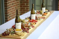 several bottles of wine are lined up on a long table with cheese and crackers