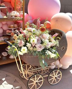 a baby carriage filled with lots of flowers next to balloons and other items in the background