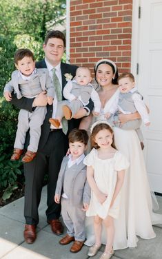 a family posing for a photo in front of a house with their two children and one adult