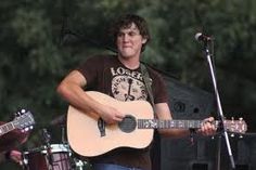 a man holding a guitar while standing next to a microphone