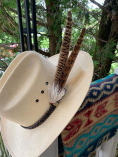 a white hat with feathers on it sitting on top of a bench next to a tree