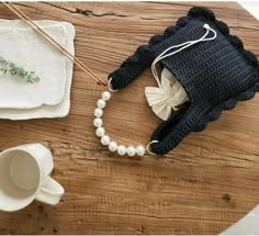 a crocheted elephant hat sits on a table next to a cup and saucer