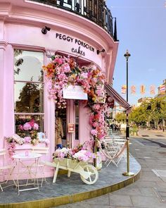 a pink store front with flowers on the outside and tables in front that are decorated