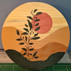 a wooden plate with an image of a tree in the sunset and mountains on it