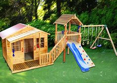 a wooden play set with a slide and swing set in the grass next to trees