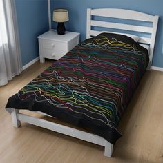 a bed with a black and multicolored comforter on top of it in a bedroom