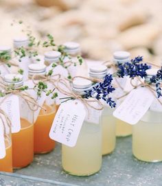 small jars filled with orange juice and lavender sprigs on top of a table