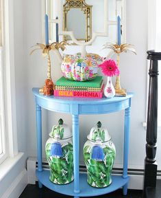 a blue table with two vases on it and a mirror in the corner behind it