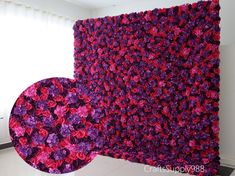 a large purple and red flowered wall hanging on the side of a white wall