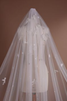 a wedding veil with white flowers and pearls on the bottom is hanging from a mannequin's head