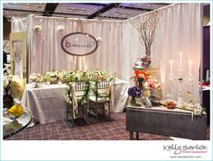 a room filled with tables and chairs covered in white cloths next to tall vases