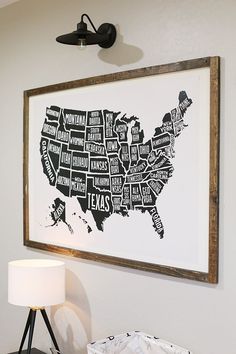 a framed map of the united states is hanging on a wall above a table with a lamp