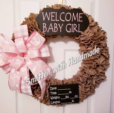 a welcome baby girl wreath with a pink bow hanging on the front door to give it a name