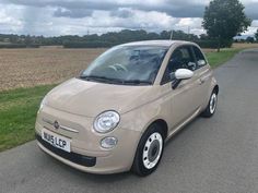 a small car is parked on the side of the road in front of a field