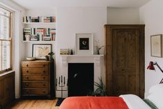 a bedroom with a bed, dresser and fireplace