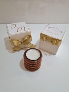 the candle is next to two boxes with gold ribbons on them, and one has a bow around it