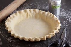 an uncooked pie crust next to a pair of scissors and a canister