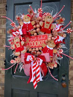 a christmas wreath with gingerbread cookies, candy canes and candies on the front door