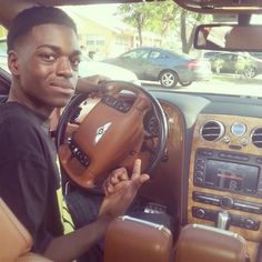 a man sitting in the driver's seat of a car holding a steering wheel