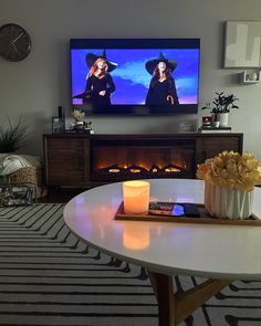 a flat screen tv sitting on top of a white table next to a fire place