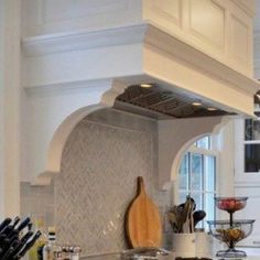 a kitchen with white cabinets and an island in the middle is filled with cooking utensils