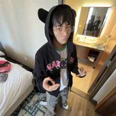 a young boy wearing a black bear hoodie standing in front of a bedroom mirror