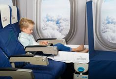 a little boy sitting in an airplane seat with his feet up on the table next to him