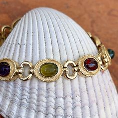 Estate/ vintage 14KT yellow gold Byzantine design, textured + cabochon, multi-gemstone link bracelet. Textured, shiny, and matte finishes on this piece. Slightly concave pieces with cabochon, amethyst, blue topaz, garnet, peridot, and citrine oval gemstones. Each gemstone measures: 7mm x 5mm; (8) total Rectangle byzantine + shiny open design links bracelet Measures 7.5", but fits shorter when clasped at the shorter length Weight: 22 grams Measures: 10mm wide Secure snap clasp Stamped 14K Great v Gold Cabochon Gemstones For Formal Occasions, Yellow Gold Oval Link Jewelry With Gemstone, Elegant Oval Jeweled Bracelets, Elegant Oval Jeweled Bracelet, Oval Gold Bracelet With Gemstone Accents, Oval Gold Bracelets With Gemstone Accents, Gold Oval Bracelets With Gemstone Accents, Gold Oval Bracelet With Gemstone Accents, Gold Jewelry With Gemstone Accents In Oval Cabochon