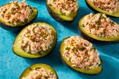 stuffed avocados filled with tuna salad on a blue tablecloth, ready to be eaten