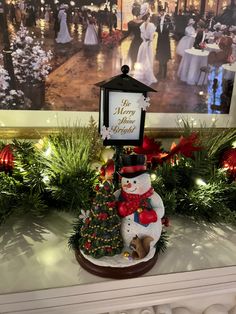 a snowman is standing next to a christmas tree with a sign that says the merry season