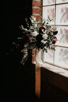 a bouquet of flowers sitting on top of a window sill next to a brick wall